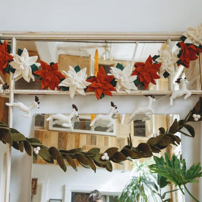 Green felt mistletoe garland with white berries hanging with other holiday garlands.