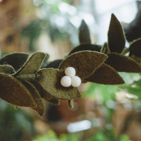 Close up of white berries on green felt mistletoe garland.