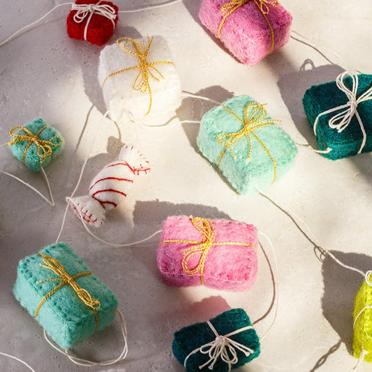 Close up of felt garland of gifts in pink, teal, red, green and white.