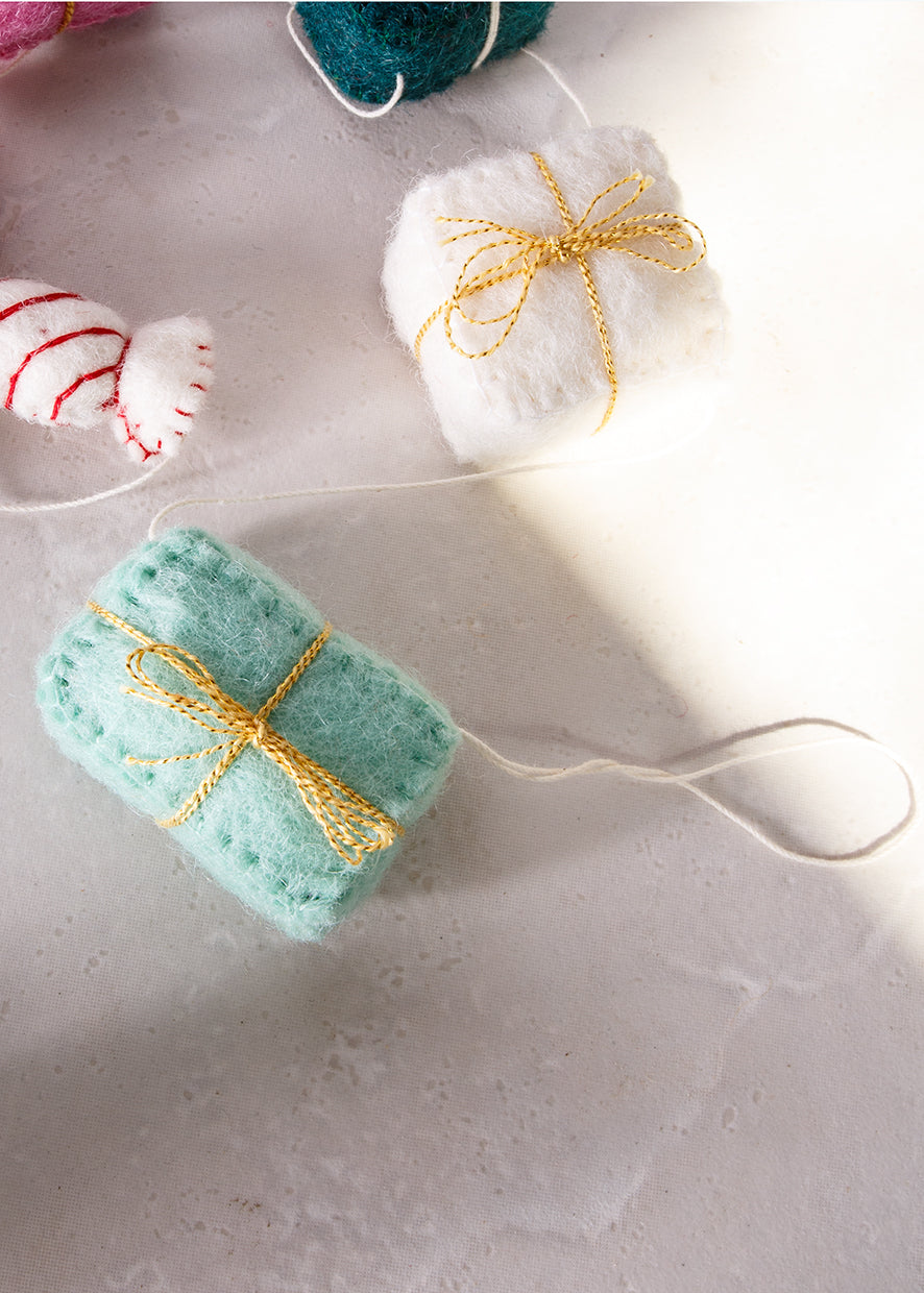 Close up of felt garland of gifts in pink, teal, red, green and white.