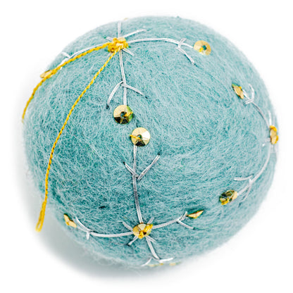 A round, light blue felt ornament with white embroidery and gold sequin designs.