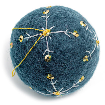 A dark blue round felt ornament with white embroidery and gold sequin designs.