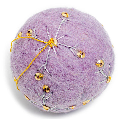 A purple round felt ornament with white embroidery and gold sequin designs.