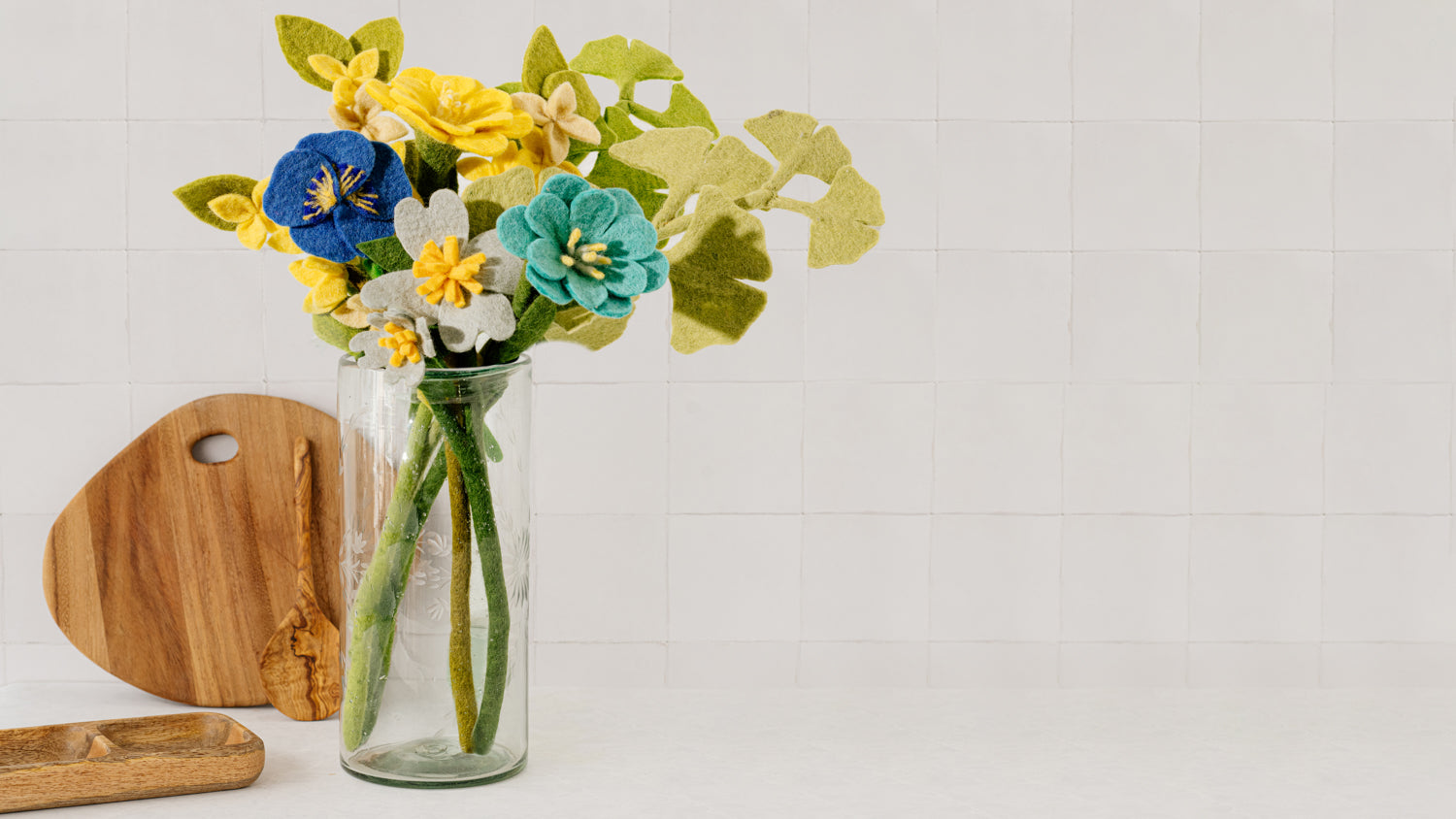 Etched clear glass vase with blue, yellow, green felt flowers.