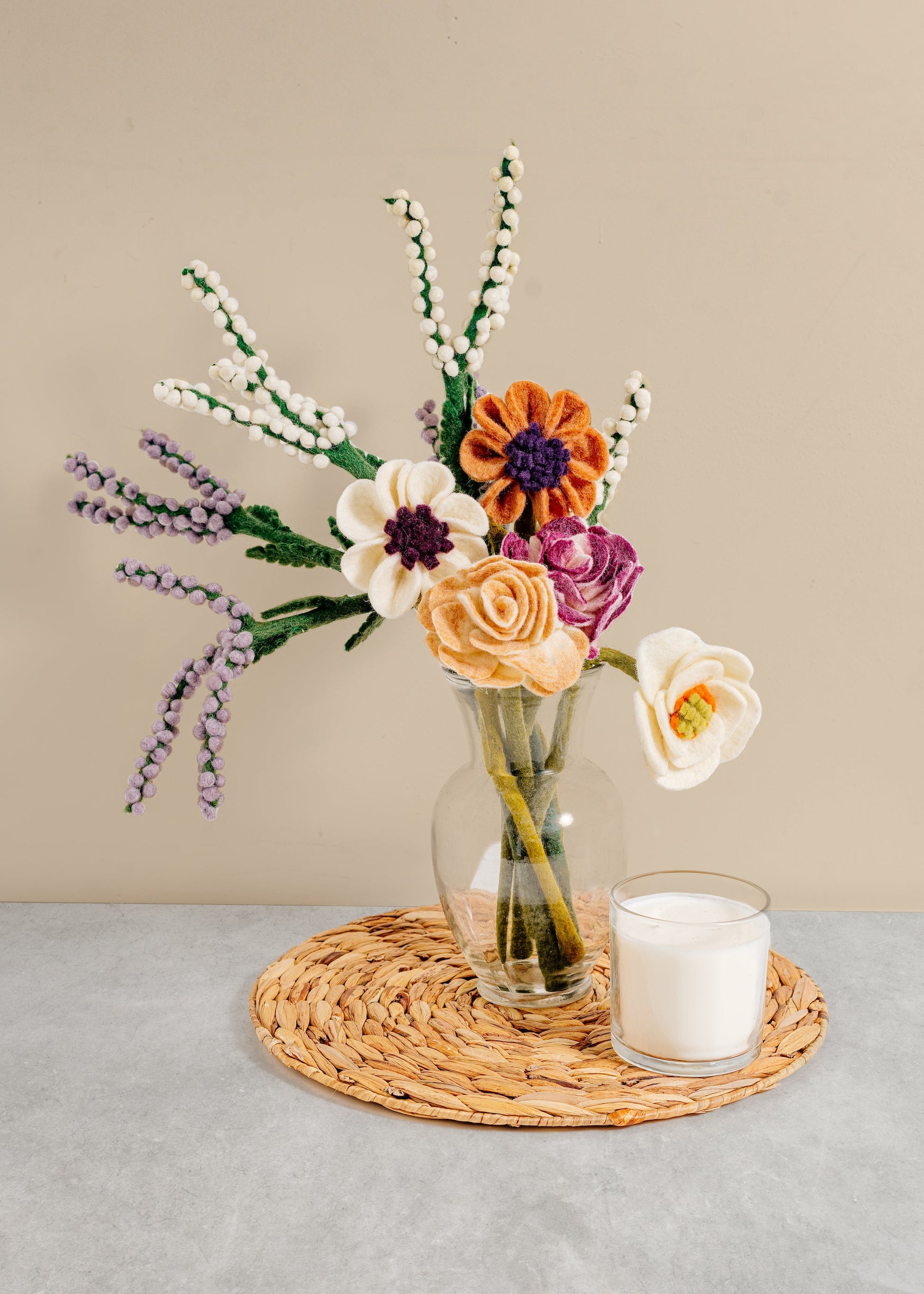 White, orange, cream and purple felt ranunculus flowers with other various flowers in a white vase.