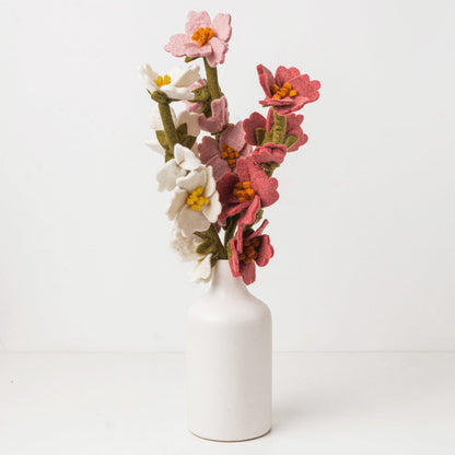 Pink, white, and green felt floral arrangement in a white vase.