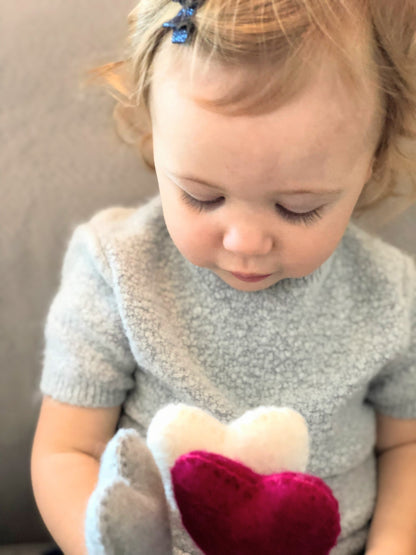 Felt heart accent stems in white, and red shown being held by baby in blue dress.