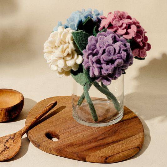 Bunch of felt hydrangea flowers in white, blue, pink and purple in a white vase.