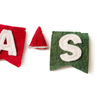Close up of the "A" and the "S" with a Santa hat between from the felt garland spelling out Santa Stop Here in red and white letters on small dovetail flags in white, red, and green.