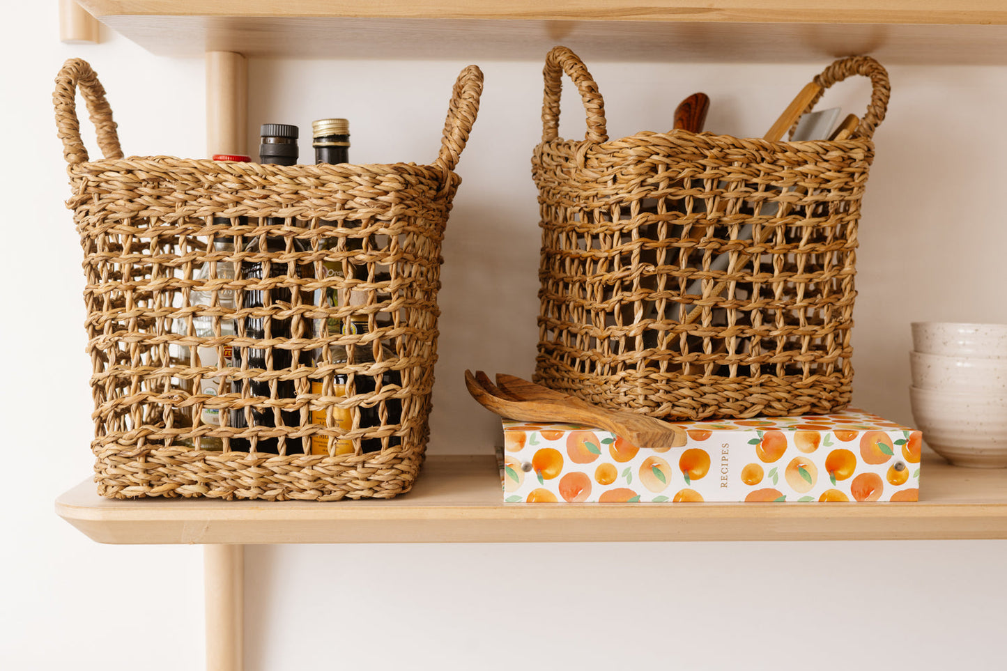 Set of two brown woven baskets with net design on shelf.