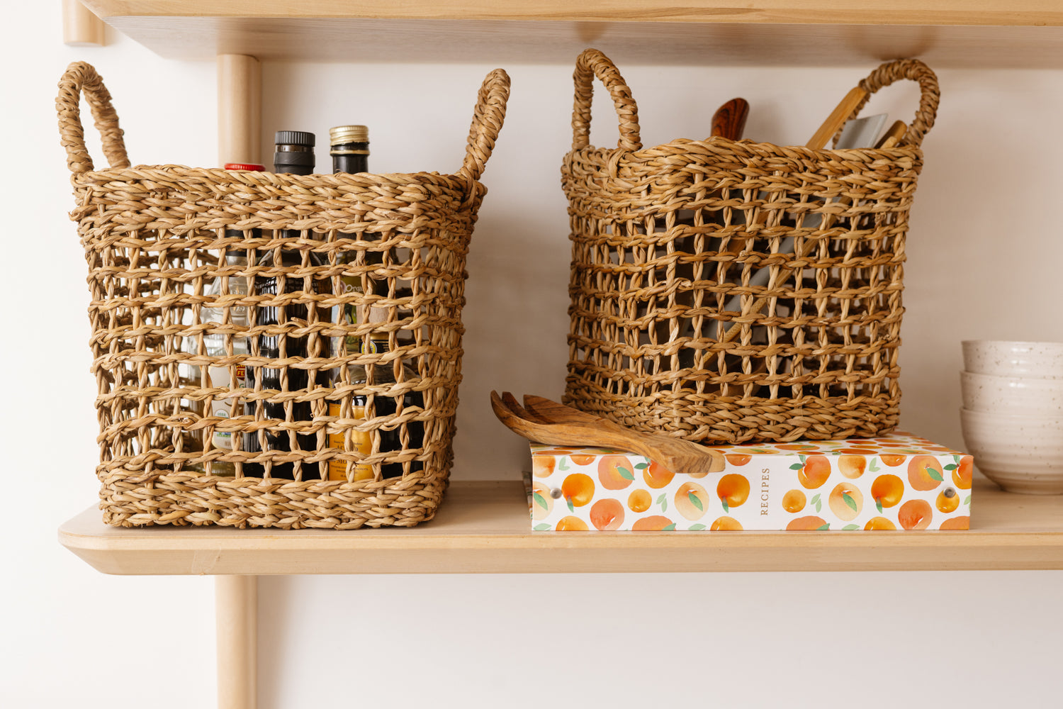 Set of two brown woven baskets with net design on shelf.