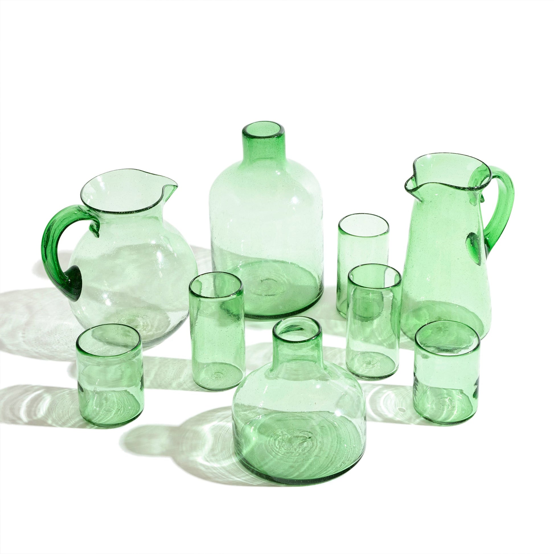 Group of short green glass vase with tall green glass vase, pitchures and glasses.