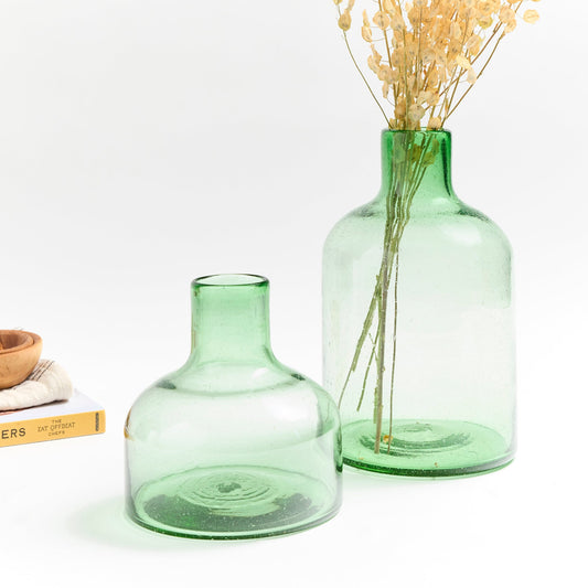 Short green glass vase with tall green glass vase holding yellow flowers.