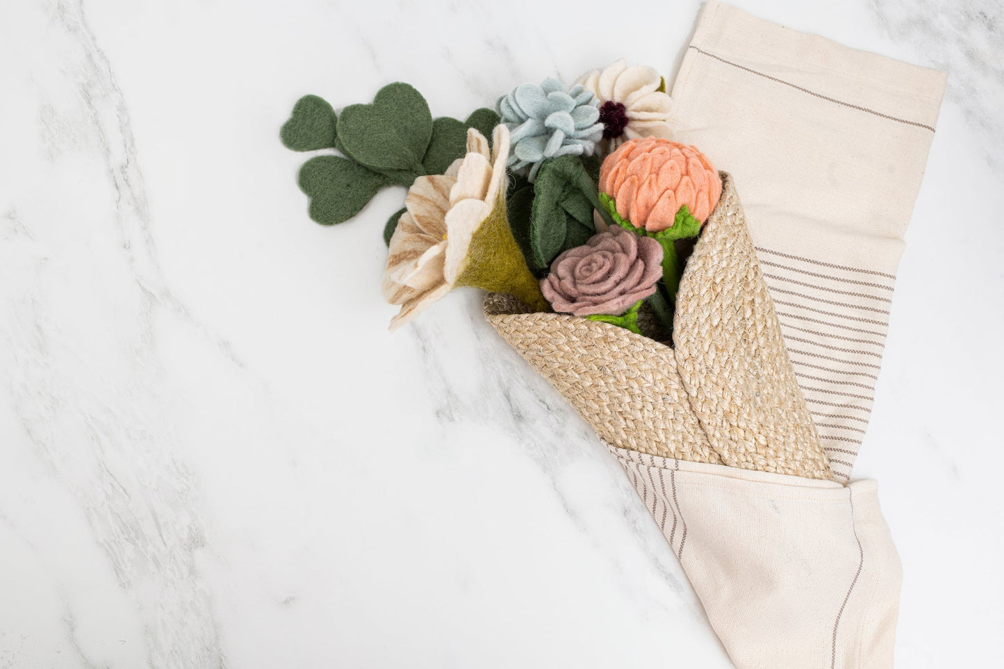 Brown woven wall cone vase with felt flowers on tea towel.