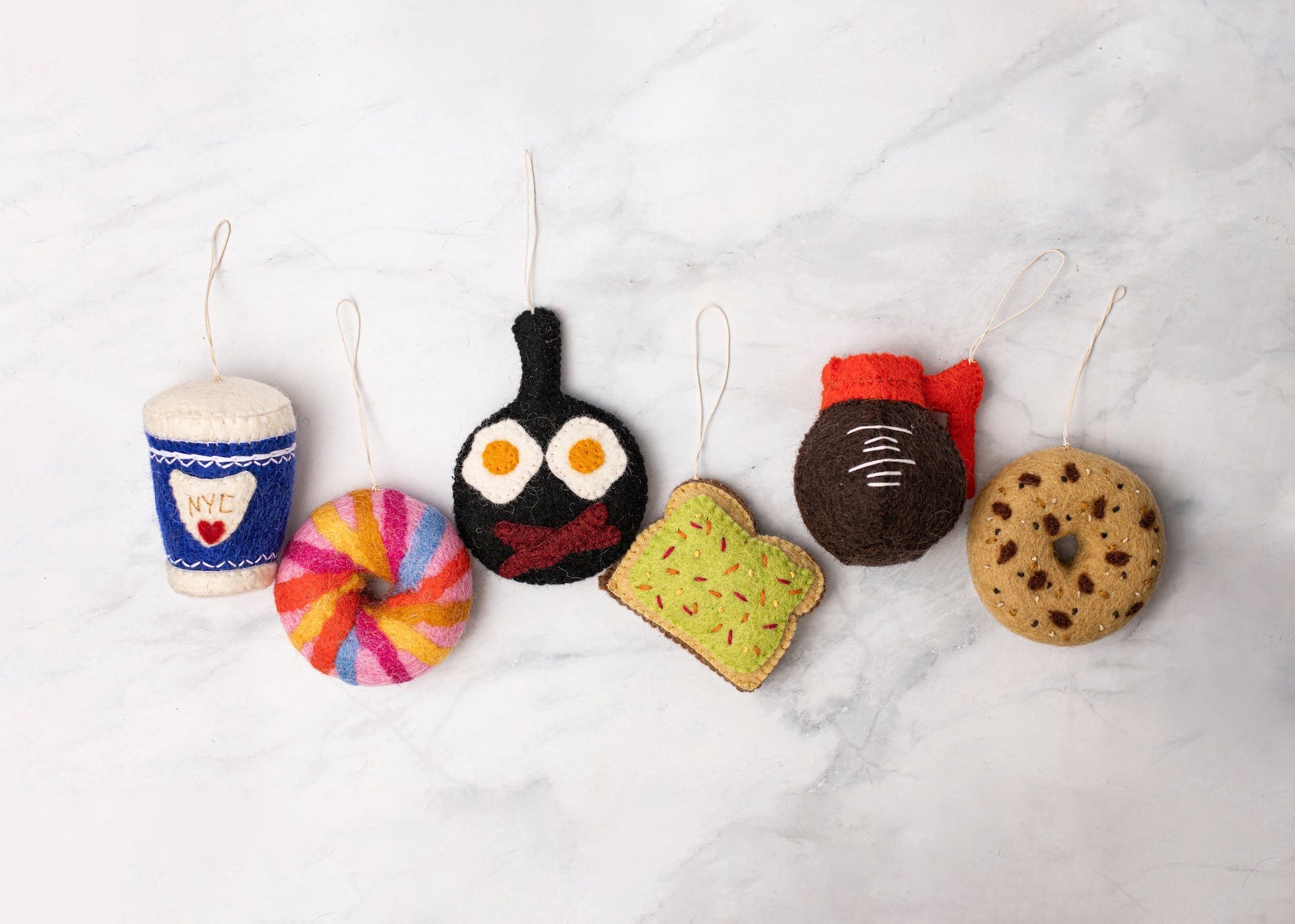 Felt ornament of a NYC rainbow bagel with other food ornaments.