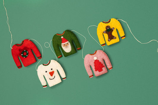 Garland of tiny sweaters, one red with a wreath, white with snowman, pink with red tree, green with Santa, and yellow with a gingerbread man.