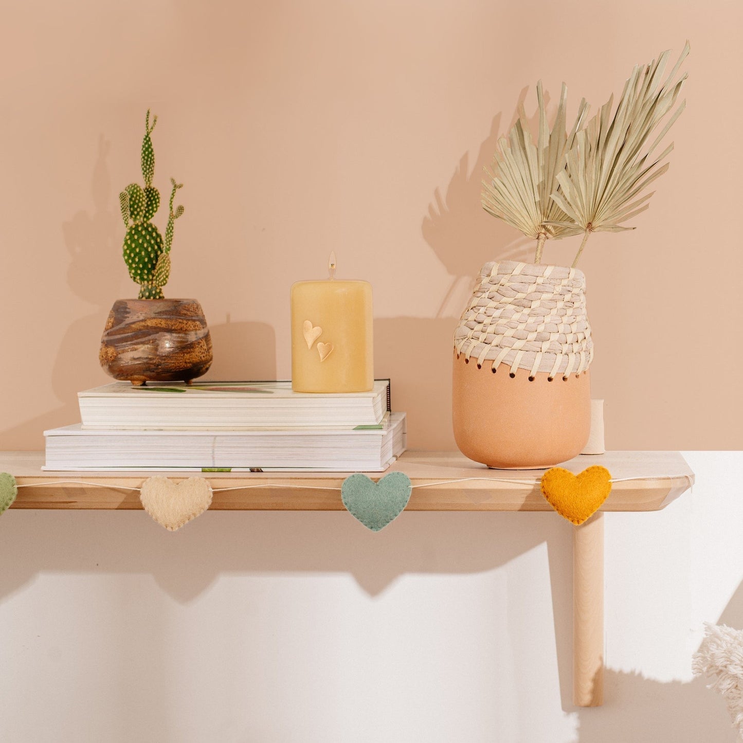 Felt garland of hearts in alternating colors of peach, teal and orange hanging on mantel.