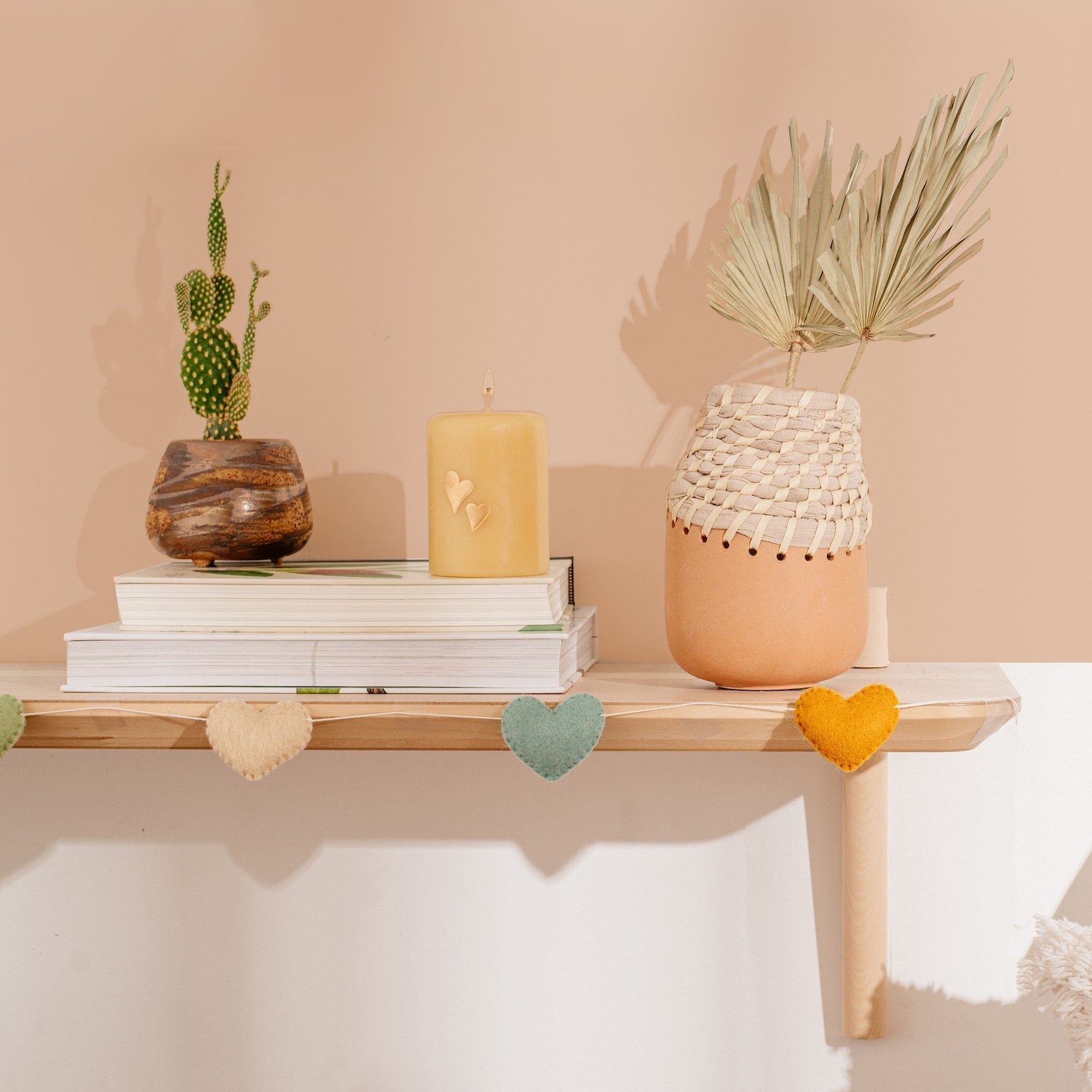 Felt garland of hearts in alternating colors of peach, teal and orange hanging on mantel.