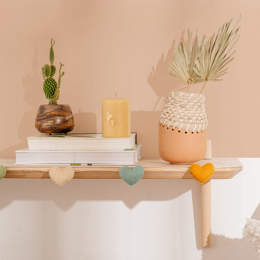 Felt garland of hearts in alternating colors of peach, teal and orange hanging on mantel.