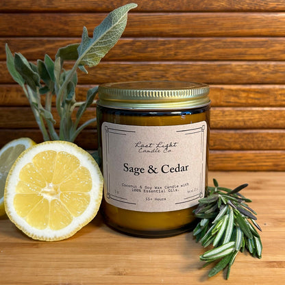 Sage and Cedar Primary Photo Izela.  Amber jar with gold lid on wood table with lemon and herb branches.