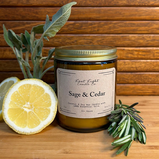 Sage and Cedar Primary Photo Izela.  Amber jar with gold lid on wood table with lemon and herb branches.