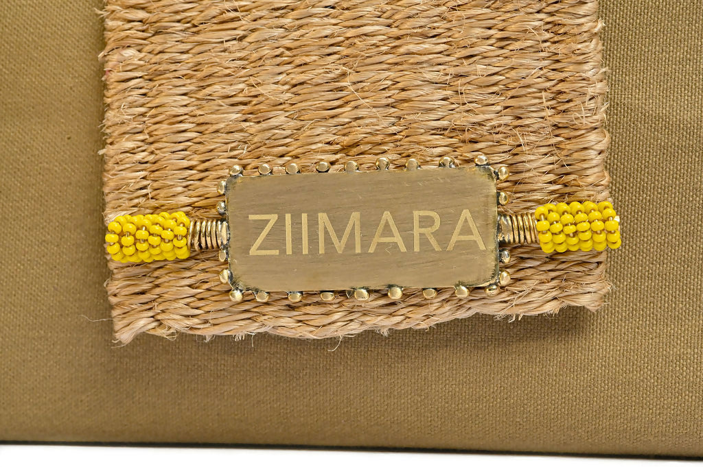 Closeup view of sandstone green bag closing flap with brass details.