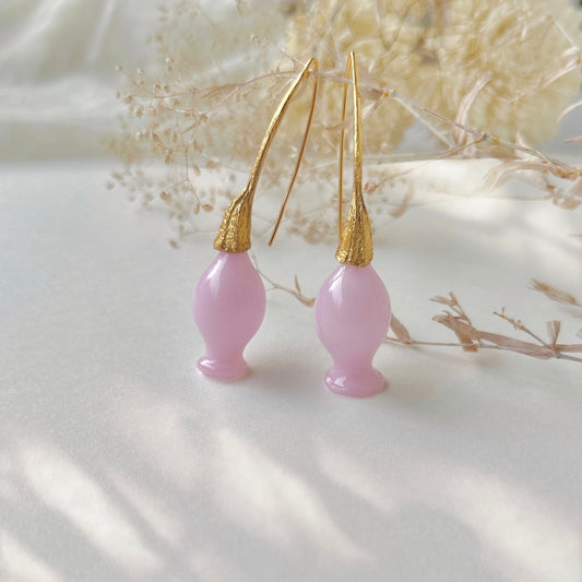 Pair of pink glass earrings with gold plated findings. Dried flowers in upper area of image.