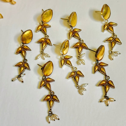 Group of seven gold foil earrings with geometric design.