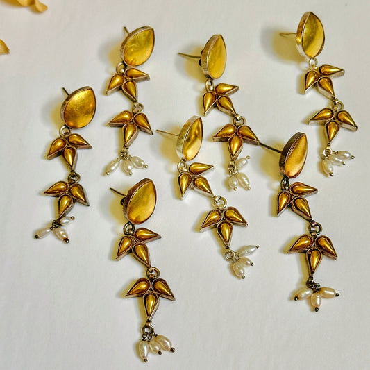 Group of seven gold foil earrings with geometric design.