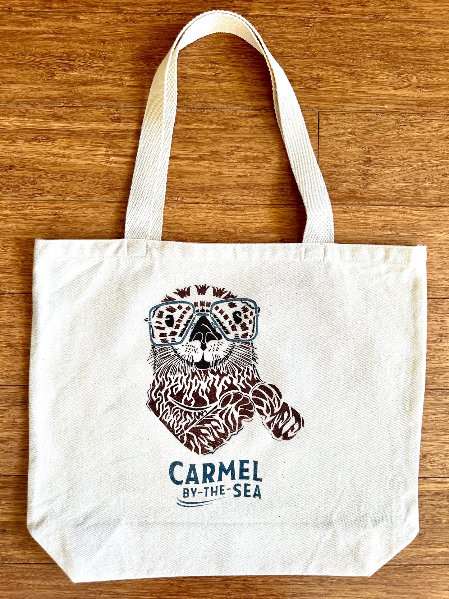 Canvas tote bag with picture of an otter and carmel-by-the-sea written below.