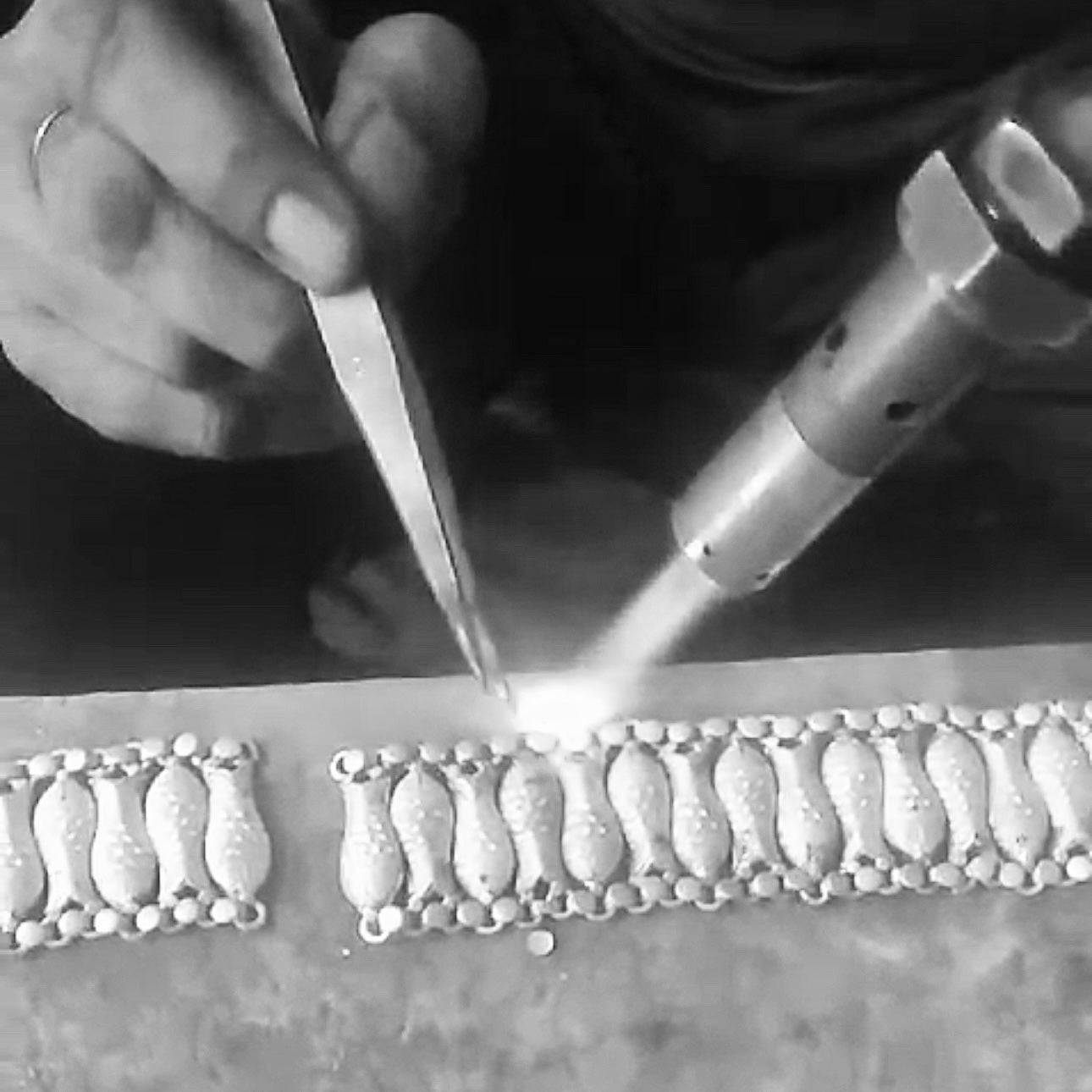 Artisan working on Silver and pearl dangle earings with fish motif.