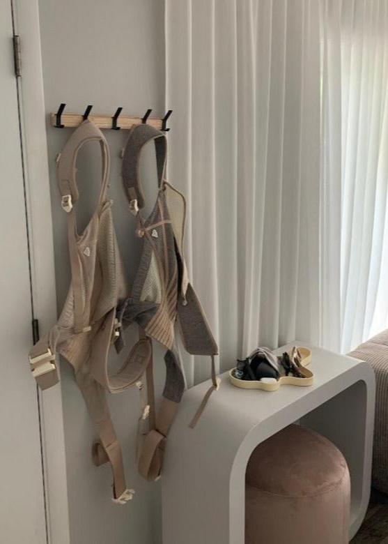 The Corset Carrier Latte hanging on hooks by a door.