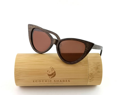 Bamboo frame cat eye sunglasses with dark brown frame and lenses sitting on cylindrical bamboo case.