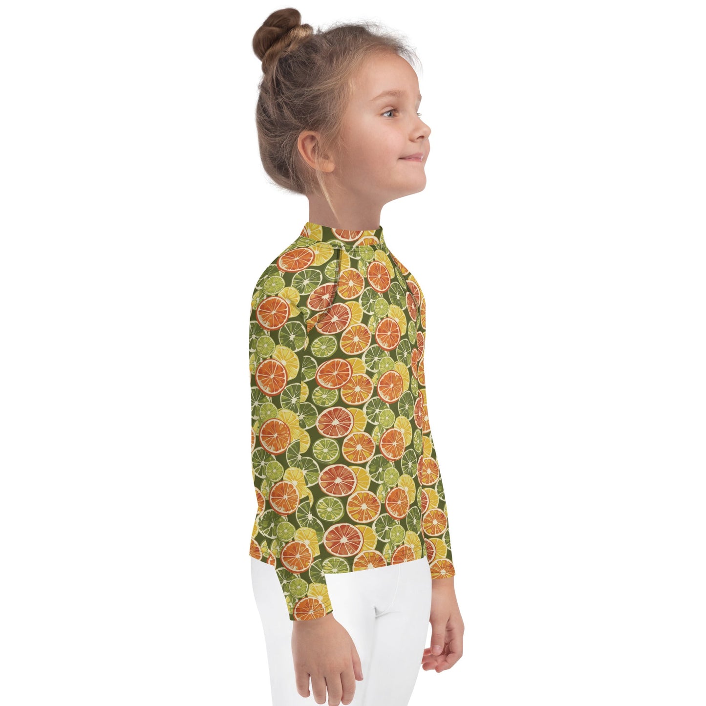 A kids’ citrus rash guard with playful orange and green fruit motifs on a white base, shown from the side.