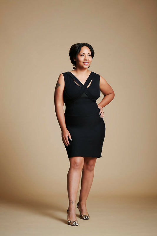 Women posed with left hand at waist, right leg slightly forward, wearing a black dress.