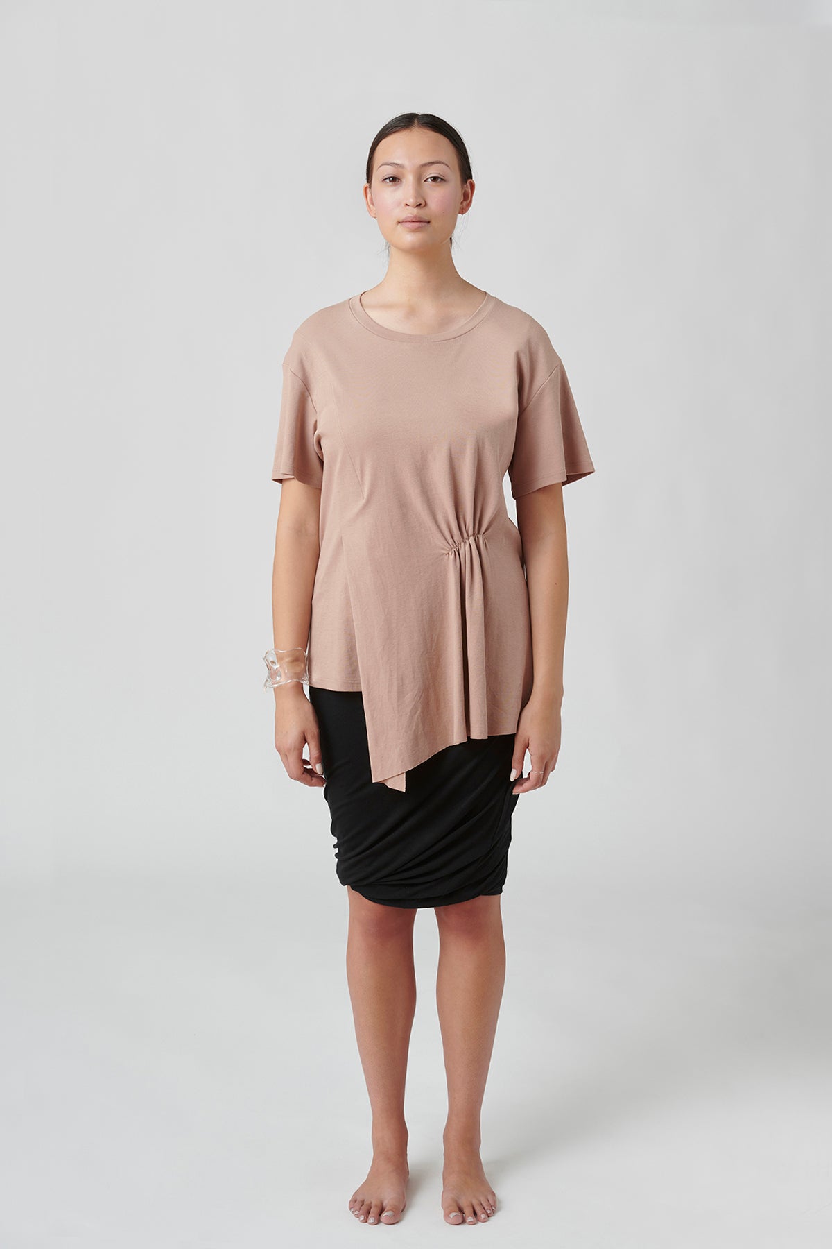 Front view of woman wearing taupe tee and black skirt.