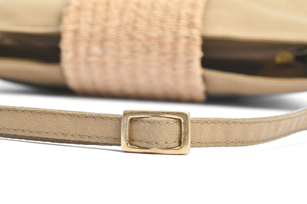 Closeup view of sandstone green bag and strap with brass buckle.