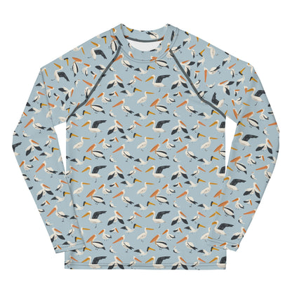 A teen’s rash guard featuring a playful pelican print with shades of blue and white, shown from the front.