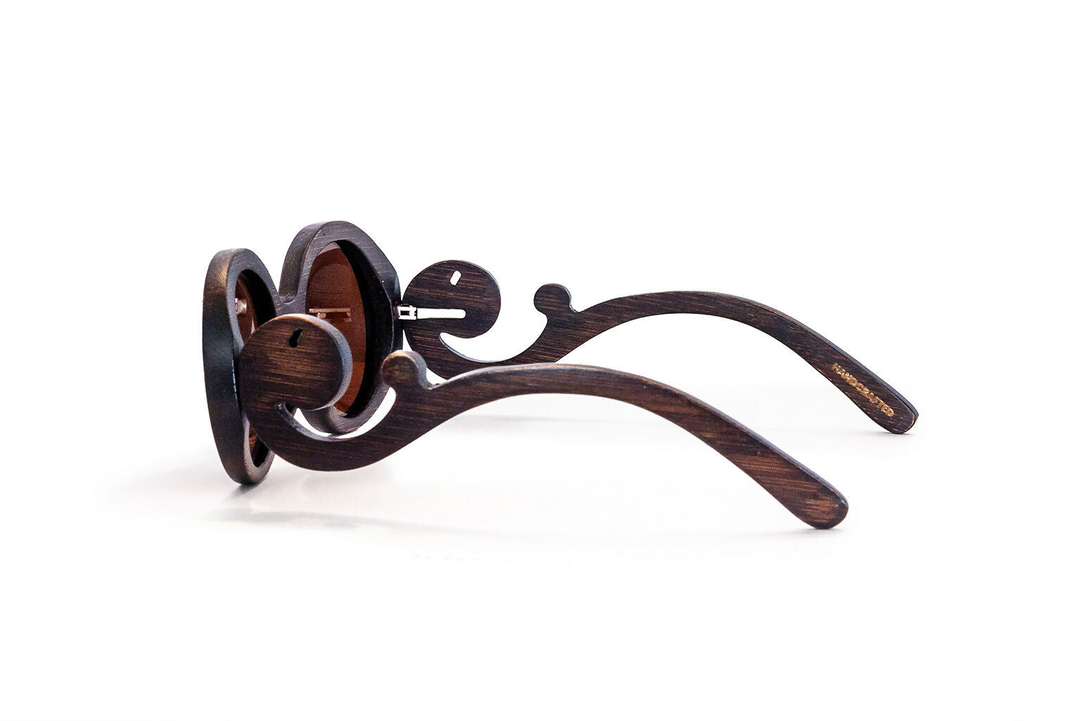 Side view of brown bamboo sunglasses with brown lenses with scroll like design on arms.