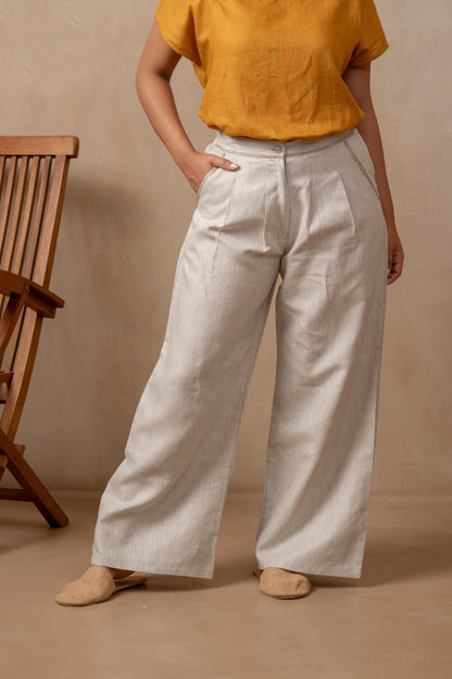 Partial view of woman wearing Dhara | Pleated Wide Leg Pants in Natural Hemp and orange shirt.  Right hand is in pocket.