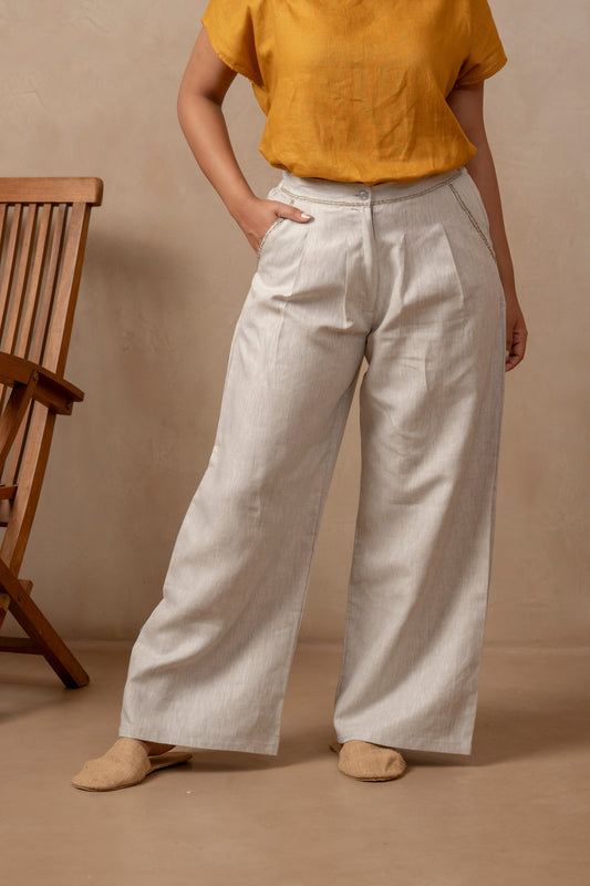 Partial view of woman wearing Dhara | Pleated Wide Leg Pants in Natural Hemp and orange shirt.  Right hand is in pocket.