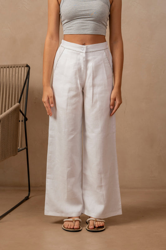 Partial front view of woman wearing white Dhara Pleated Wide Leg Pants and a crop top, hands at her side.