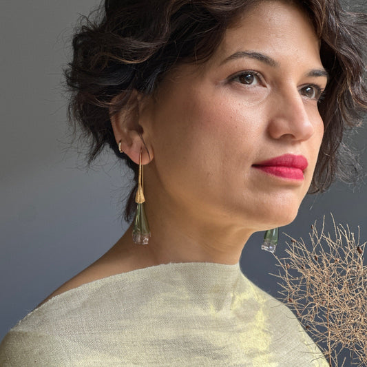 Front right view of woman wearing green and pale pink glass earrings with gold colored findings.