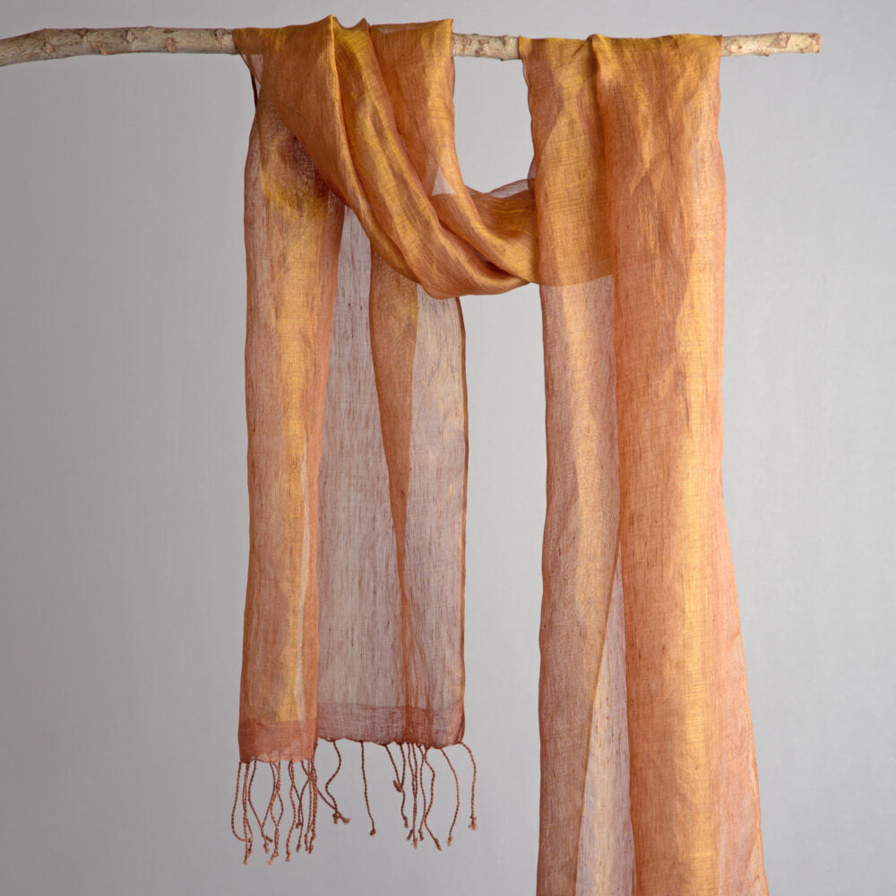 Rust orange handwoven linen scarf with gold zari metallic threads, dyed with natural myrobalan and tea, hanging on a white background.