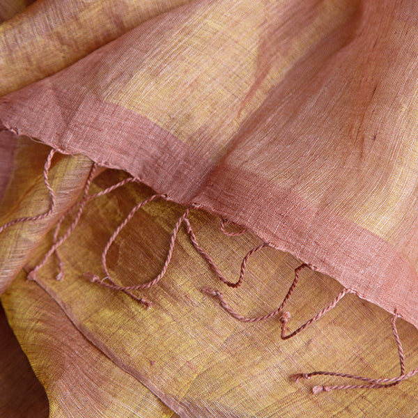 Close-up of rust orange handwoven linen scarf showing gold zari metallic threads catching the light.