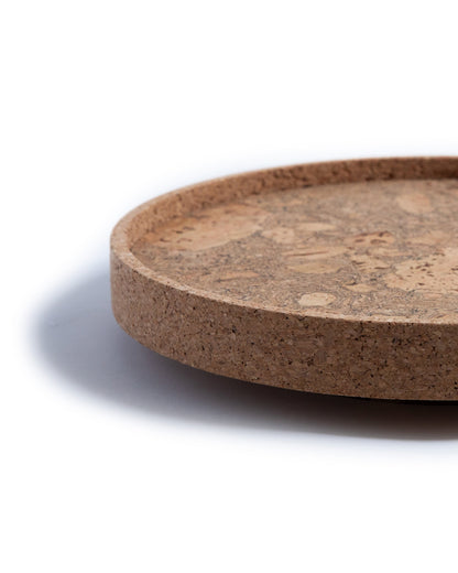 Side view close up of a circular cork Lazy Susan spinning tray with acacia wood base.
