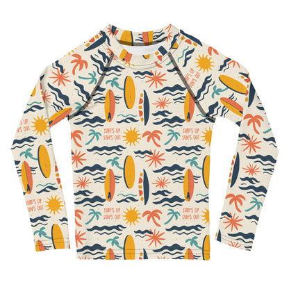 A bold rash guard with a "Surf’s Up" theme, featuring wave patterns and surfboards, shown flat from the front.