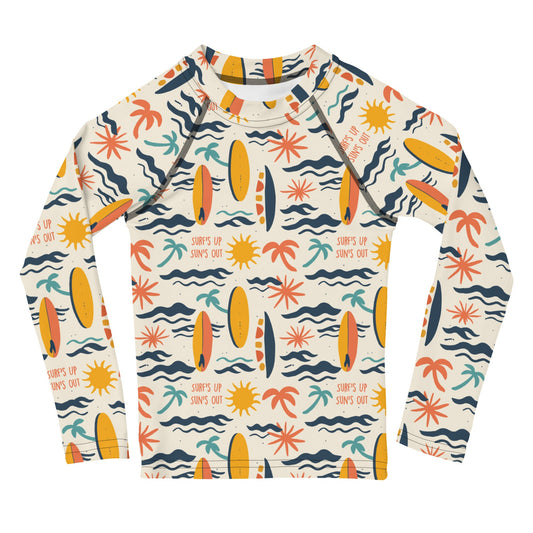 A bold rash guard with a "Surf’s Up" theme, featuring wave patterns and surfboards, shown flat from the front.