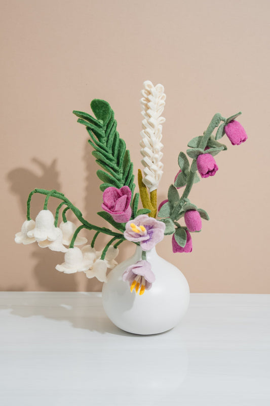 Handmade felt floral bouquet arrangement in a white vase on a beige background, made by women artisans | Global Goods Partners