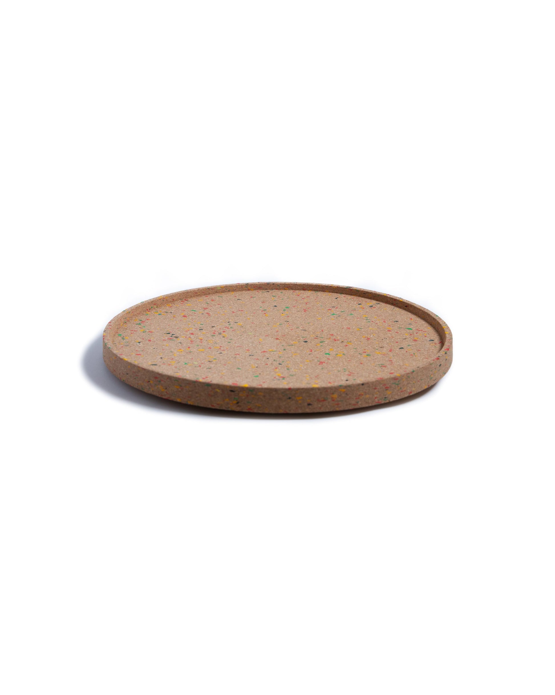 Side view of round cork serving tray with confetti bits of colored recycled plastic.